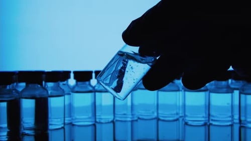Gloved Hand Holds Vial in Blue Lit Lab
