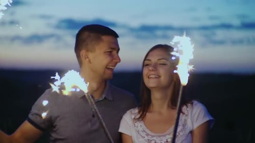 Happy Couple Laughing with Sparklers at Night