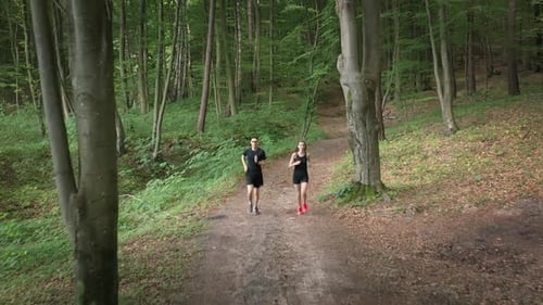 Couple Jogging on Path in the Green Forest