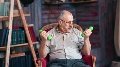Senior Adult Lifting Dumbbells in Armchair at Home