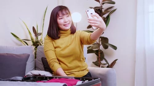 Woman Taking Selfie with Phone While Packing Suitcase