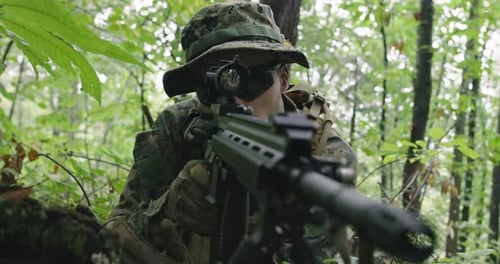 Camouflaged Soldier Aims Rifle in Lush Green Forest