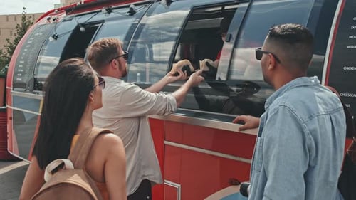 Personas que compran tacos en un camión de comida en verano