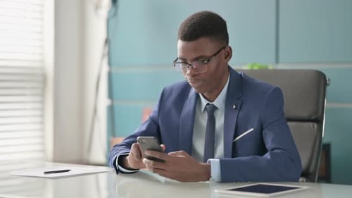 Successful Young African Businessman Celebrating on Smartphone