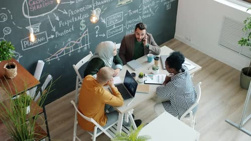 Businessman Getting Good News on Mobile Phone Doing Highfive with Excited Employees in Office