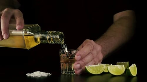 Pouring Golden Liquor into Shot Glass with Lime