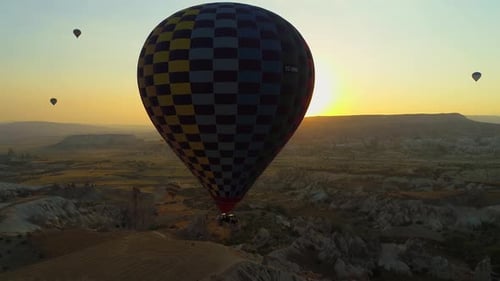 Hot Air Balloons at Sunrise Over Rocky Landscape