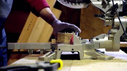 Männlicher Zimmermann schneidet das Ende des Holzbalkens mit einer Kreissäge mit Laser ab