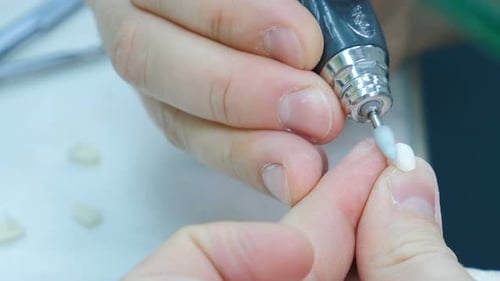 Hands Grinding Dental Crown with Dental Instrument