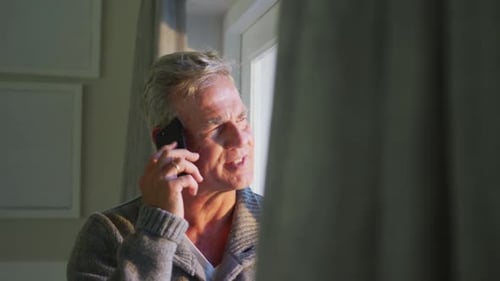 Mature Man Talking on Phone by Window