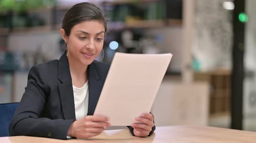 Excited Indian Businesswoman Reading Documents and Celebrating in Office