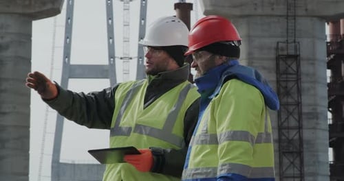 Male Engineers Discussing Bridge Drafts on Tablet