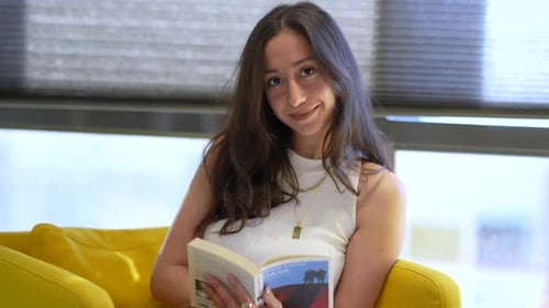Woman Reads Book on Yellow Chair Indoors