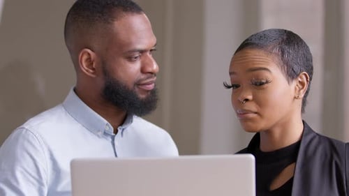 Man and Woman Collaborate on Laptop in Office
