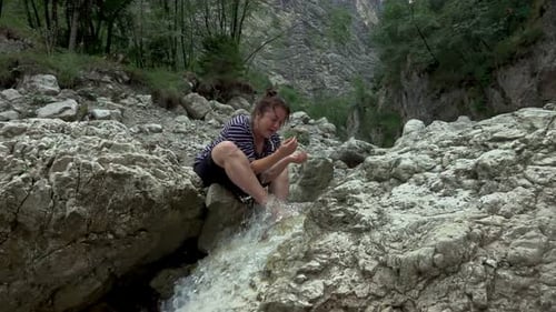 Hiker woman in a rocky valley with spring stream water in the mountain river