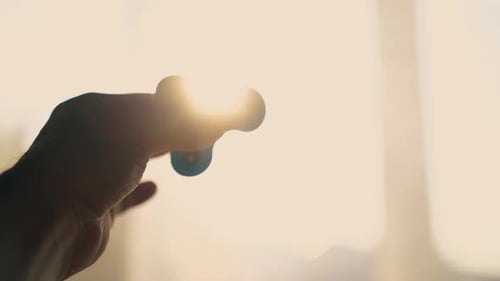 La mano del hombre sostiene el hilandero giratorio contra la luz trasera brillante