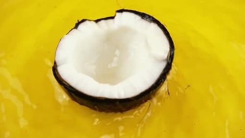 Halved Coconut Floating in Yellow Tropical Liquid