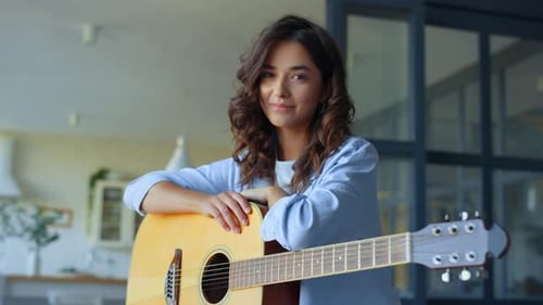Young Woman Holding Guitar Smiling Indoors