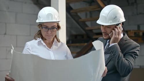 Businessman and Construction Coordinator Discussing Blueprints