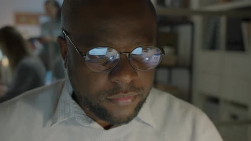 Closeup Portrait of Successful IT Specialist Working with Computer Wearing Glasses in Dark Office