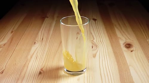 Bright Yellow Juice Poured into Clear Glass