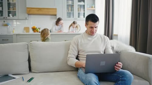 Man Working on Laptop at Home With Family