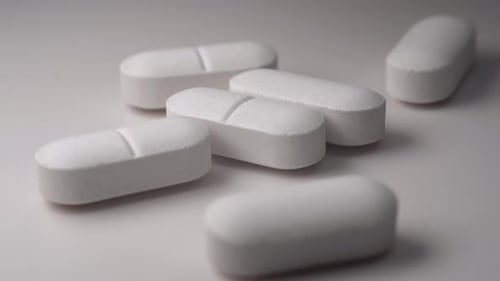 White Pills Pile Close-up on White Surface