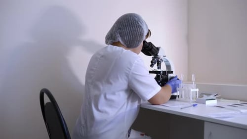 Woman Analyzing Sample Under Microscope in Laboratory