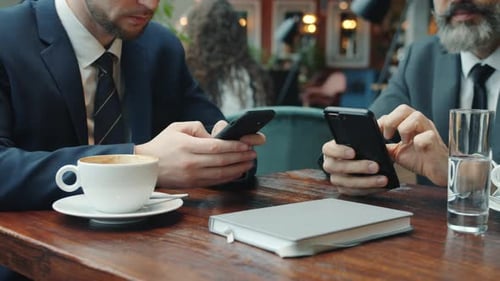 Close-up of Businessmen Using Smartphones Touching Screen in Restaurant