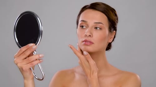 Woman Inspecting Flawless Skin with Handheld Mirror