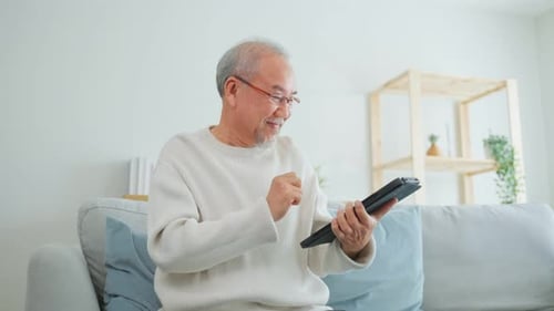 Senior Man Using Tablet Device At Home