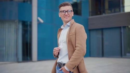 Man Smiling in Camel Coat Outside Modern Building