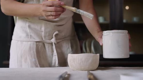 Woman Painting a Ceramic Bowl with Paintbrush