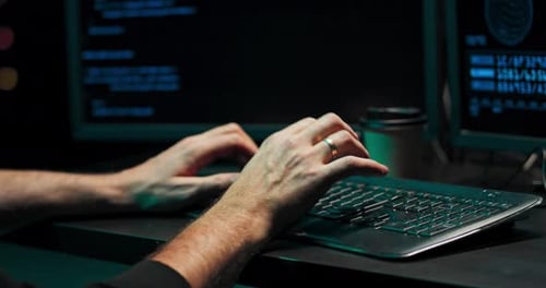 Close Up na mão de um jovem hacker que está digitando em um computador