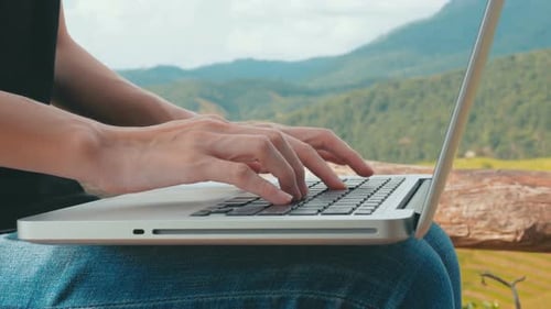 Woman Typing on Laptop in Mountainous Environment