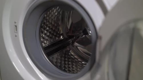 Woman Opens Door of Washing Machine Puts in Dirty Clothes and Takes Out Clothes