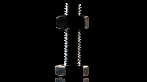 Metallic Bolt and Nut Against Dark Backdrop