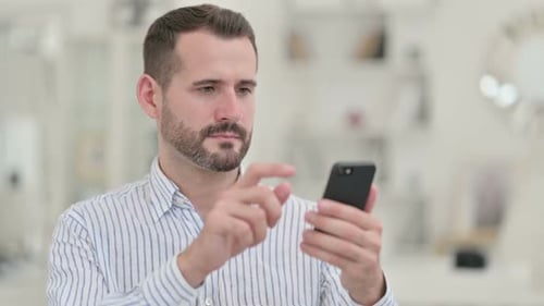 Excited Young Man Celebrates with Mobile Phone