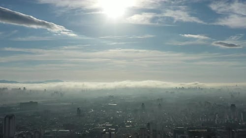 Aerial View of Foggy Cityscape Under Bright Sky