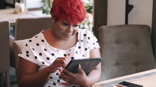 Serious Young African Businesswoman Using Tablet at Cafe