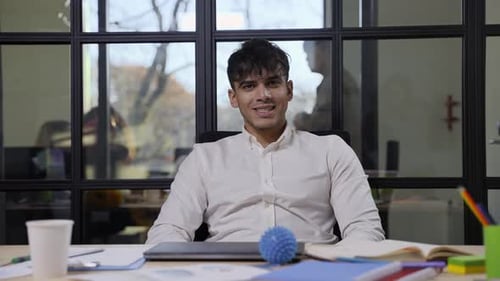 Smiling Young Adult Sits at Modern Office Desk