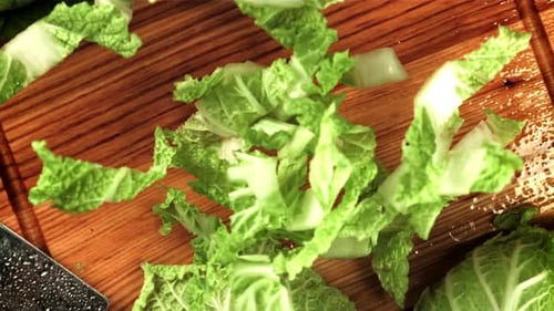 Des morceaux de chou de Pékin tombent sur la planche à découper