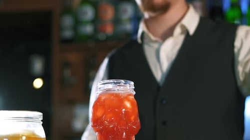Bartender Makes Red Cocktail with Ice in Skull Glass