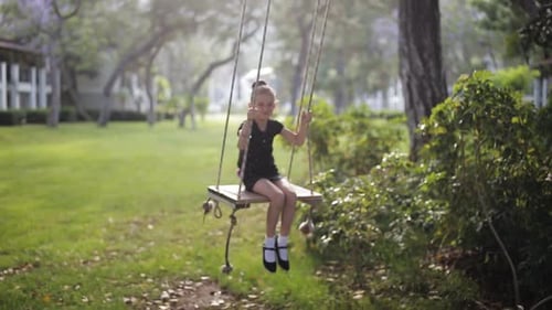 Niña pequeña se divierte meciéndose en el columpio en el parque forestal natural