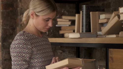 Portrait of the young pretty woman turning pages of the old book