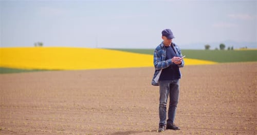 Farmer Examining Agricultural Field While Working on Digital Tablet Computer at Farm
