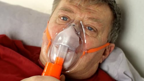 Un homme malade d'âge moyen respire lourdement à travers un masque à oxygène alors qu'il est couché