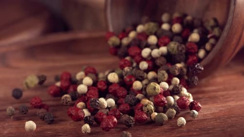 Multi Colored Peppercorns Pouring onto Wooden Surface