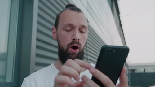 Young Adult Using Smartphone Outdoors Near Building