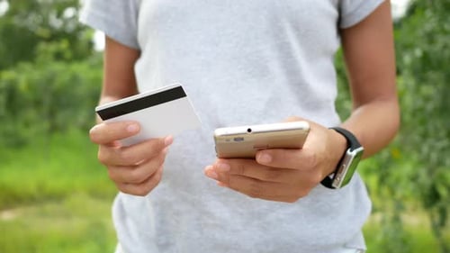Woman Holds Credit Card and Mobile Phone Outdoors